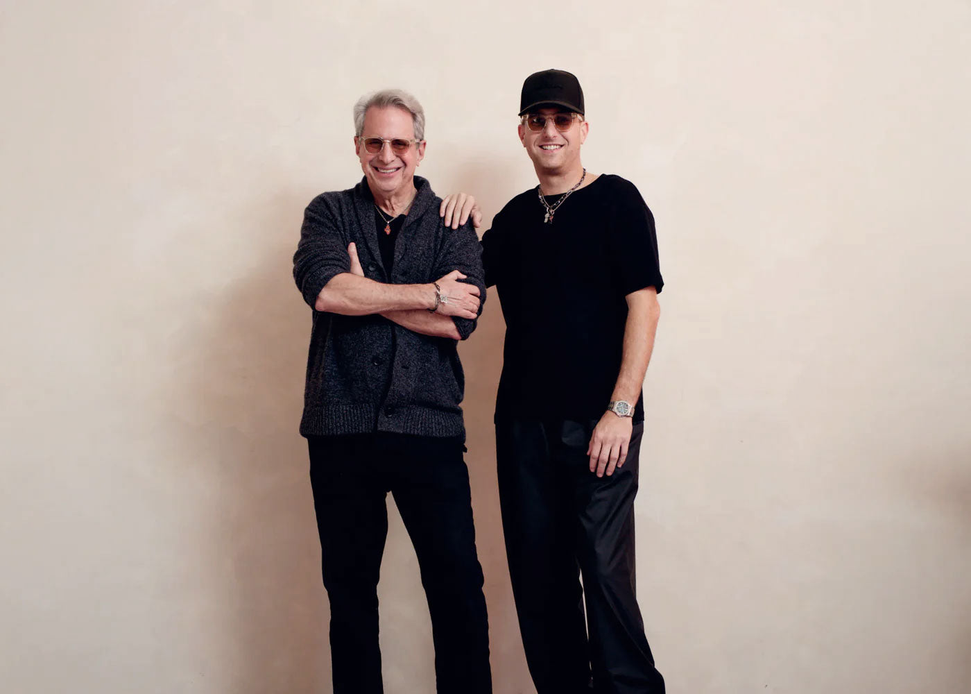 Two men standing next to each other against a beige background